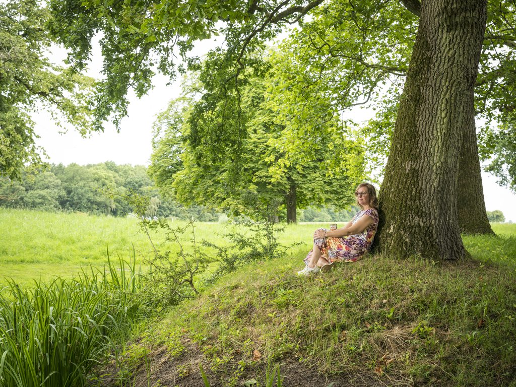 els zit op de grond tegen de stam van een boom